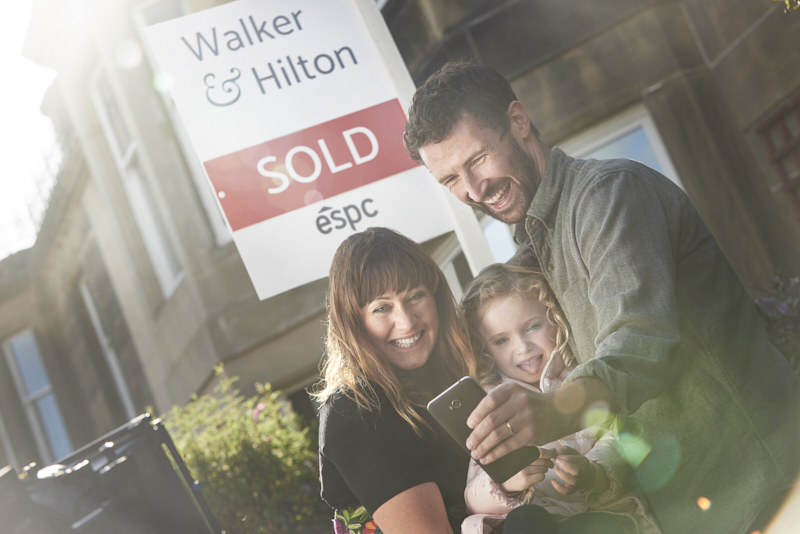 Family outside property with sold sign
